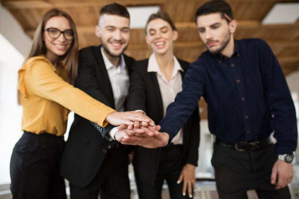 Group of smiling business partners in suits showing unity with t