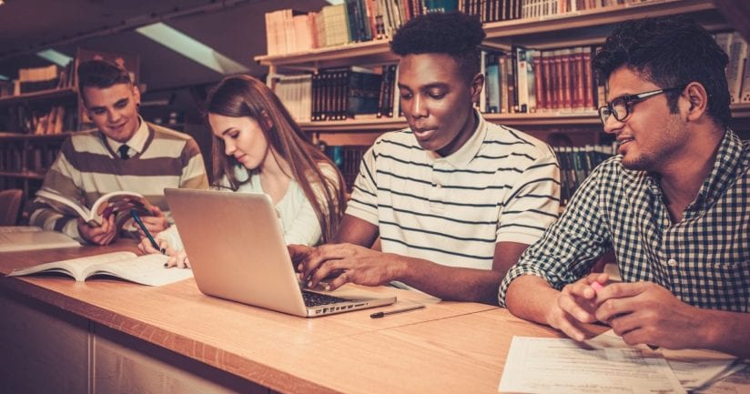 Multinational group of cheerful students studying in the university library.