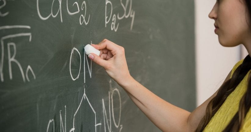 pretty young female college student writing on the chalkboard blackboard during a chemistry class